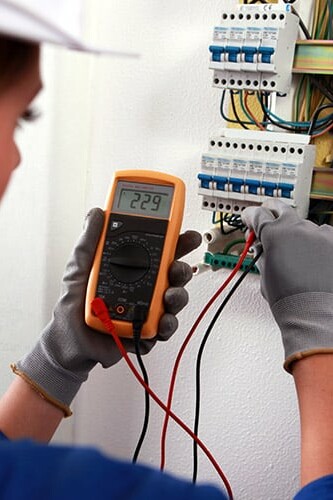 Image d'une électricienne contrôlant le compteur électrique