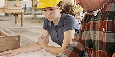 Image d'une apprentie et son tuteur travaillant sur le plan d'un bâtiment